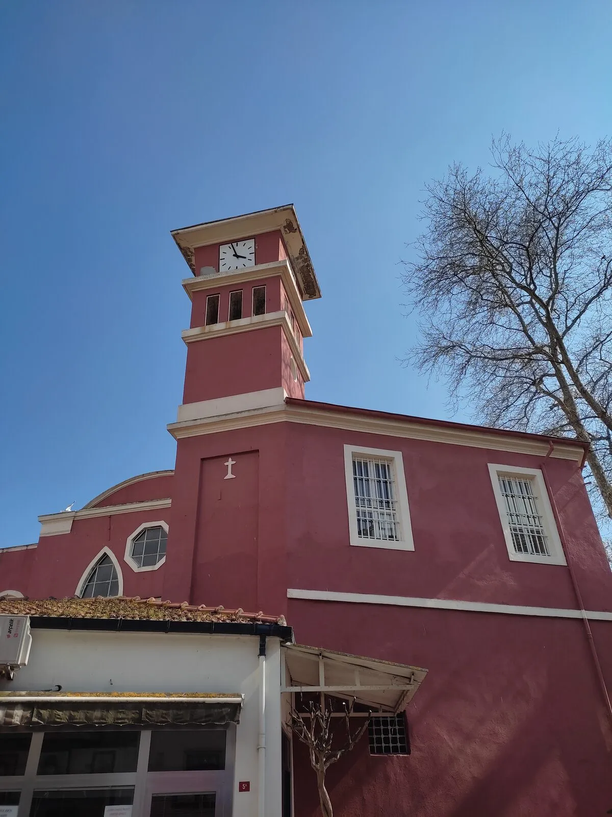 Ο κόκκινος ναός του Αγίου Νικολάου με το τετράγωνο καμπαναριό, δίπλα σε μεγάλο πλάτανο