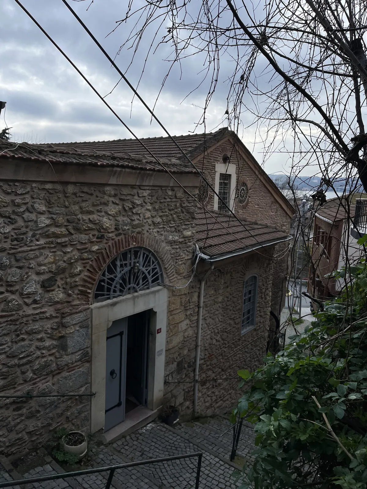 Ο πέτρινος ναός του Αγίου Δημητρίου και η είσοδός του από το κλιμακωτό δρομάκι, με τον Βόσπορο στο βάθος