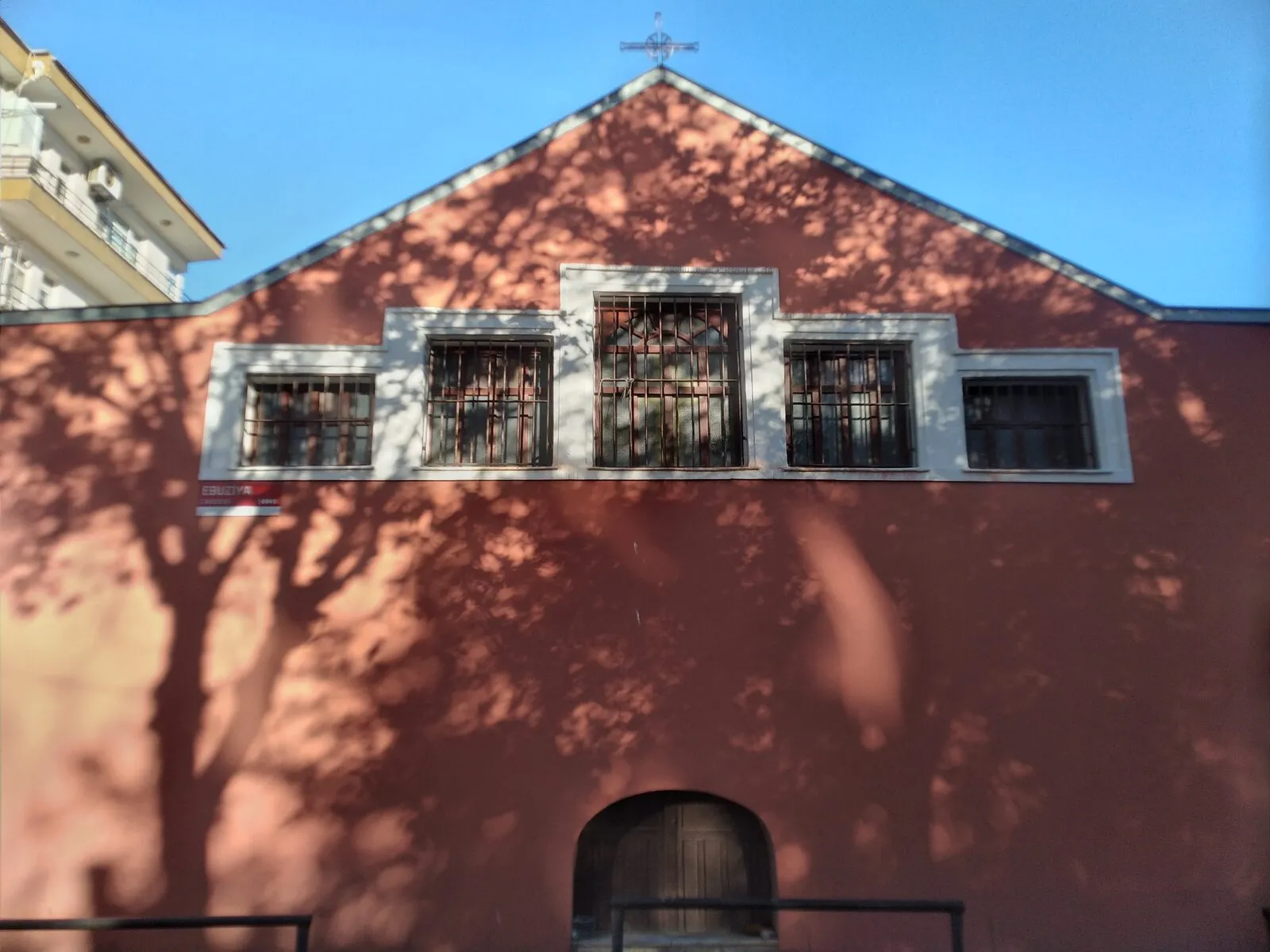 The gabled facade of the church of St George with a row of barred windows and an arched door