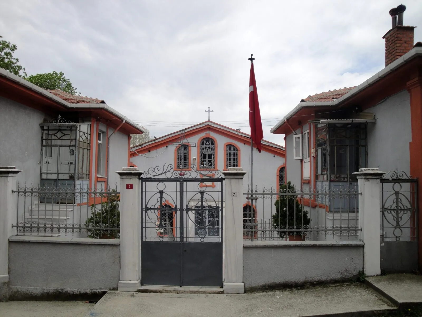 Η πύλη και η δυτική πρόσοψη του ναού ανάμεσα σε δύο σπίτια