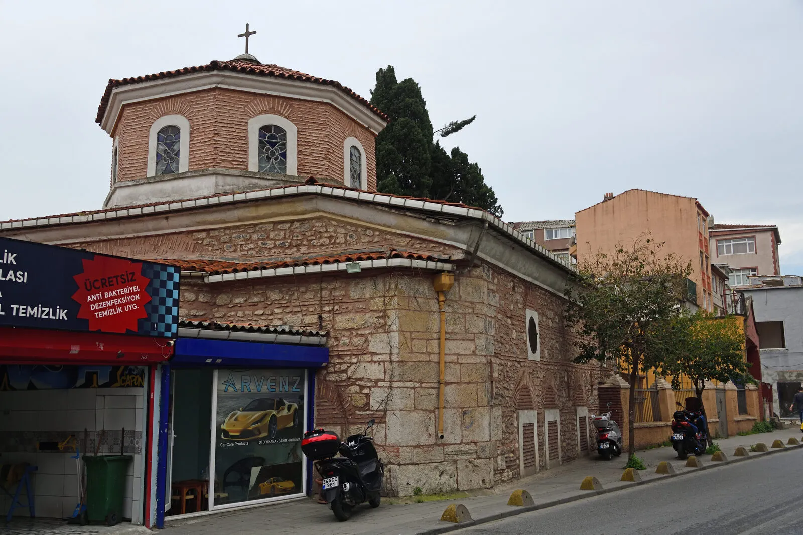 Γωνιακή όψη του ναού με τους πέτρινους τοίχους και το τύμπανο με τοξωτά παράθυρα